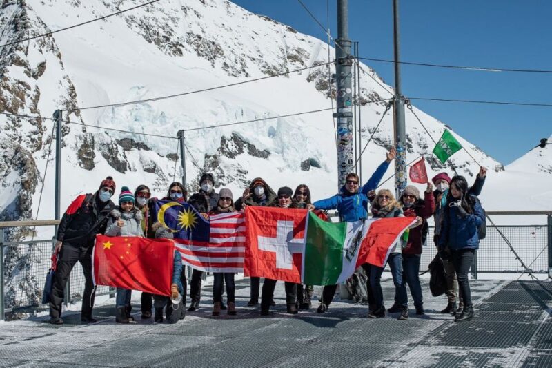 From Interlaken: Day Trip to Jungfraujoch by Bus and Train - Posing With the Swiss Flag